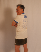 Person wearing a beige regular fit t-shirt with text and graphics, standing against a plain background