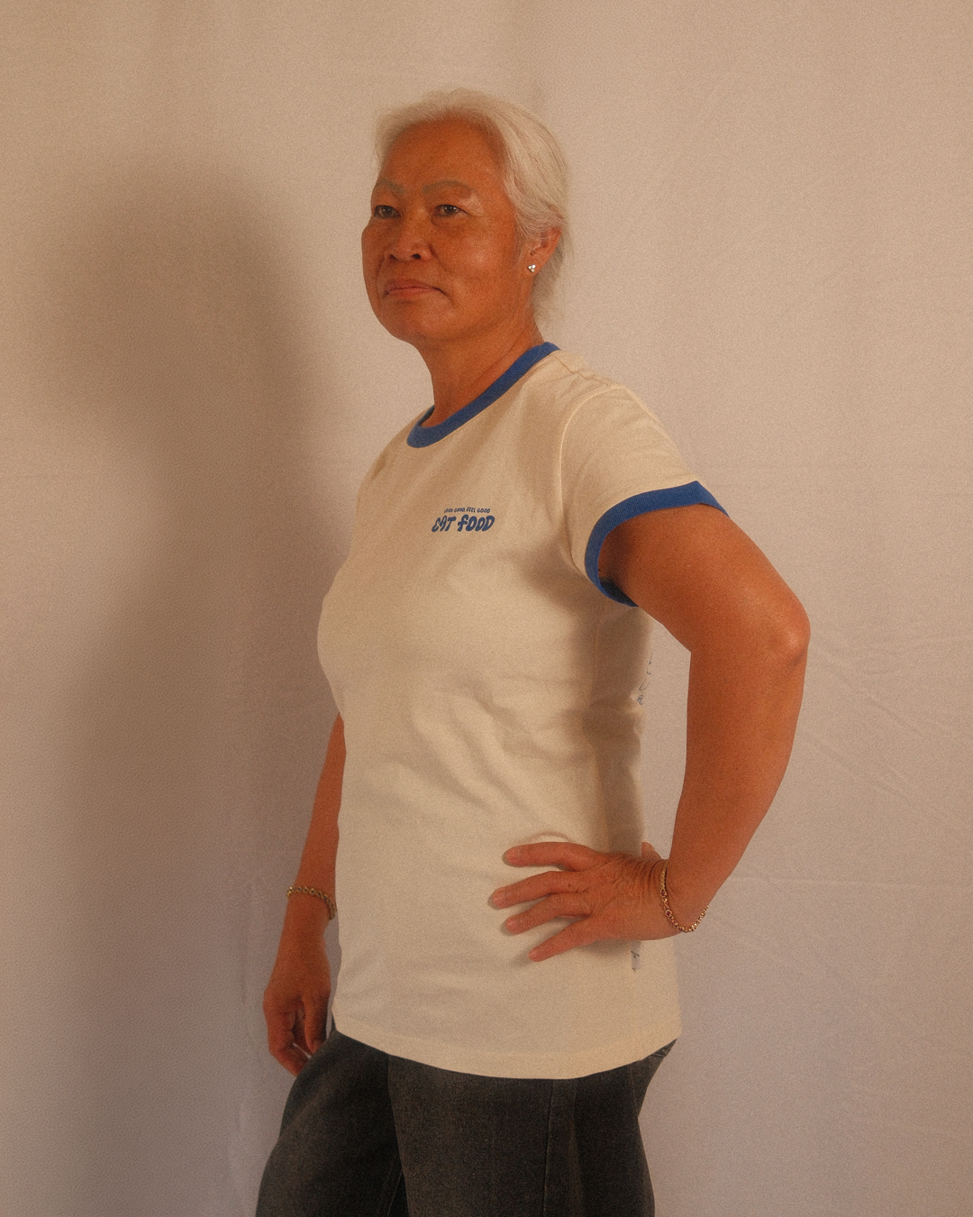 Person wearing a beige regular fit t-shirt with blue trim against a plain background