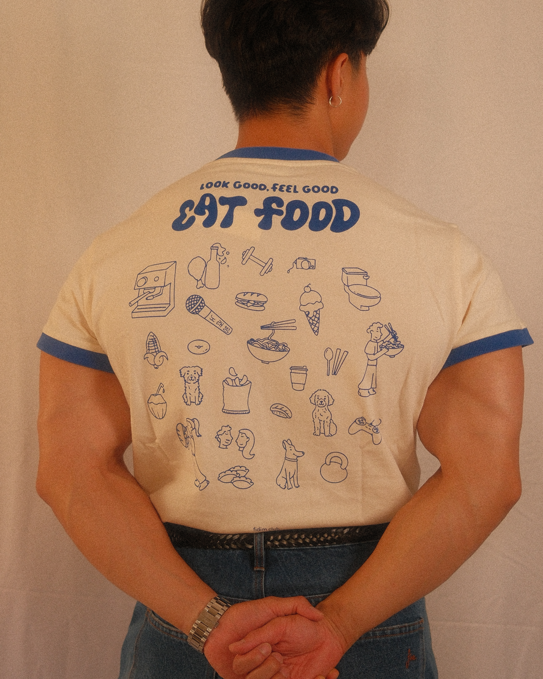 Person wearing a regular fit t-shirt with illustrations and text on the back against a plain background